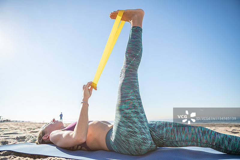 年轻女人在户外用阻力带和运动垫锻炼图片素材