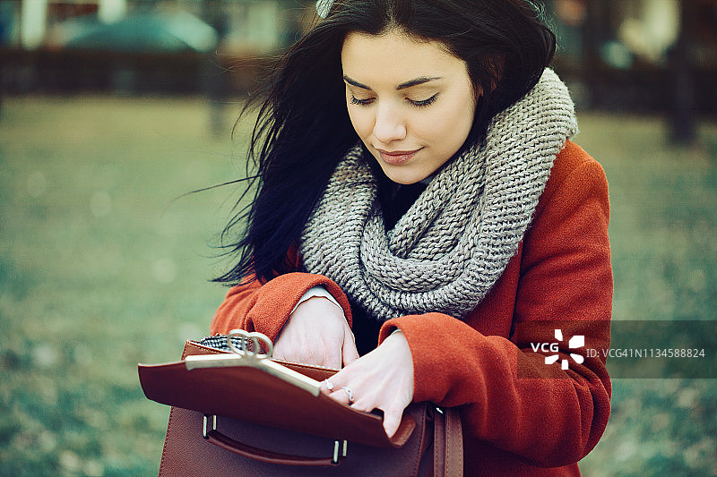 漂亮的女人在钱包里寻找东西图片素材