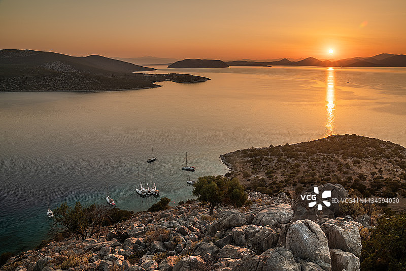 希腊埃伊纳岛的岩石岛屿和游艇的绚丽日落图片素材