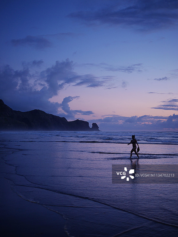 一位年轻女子独自走在贝壳海滩上图片素材
