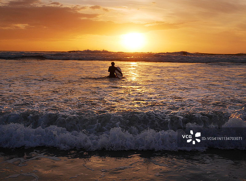 两名冲浪者欣赏贝瑟尔斯海滩的日落图片素材