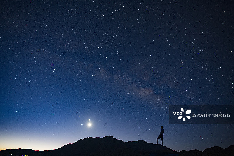 银河背景下高岩上的人的剪影图片素材