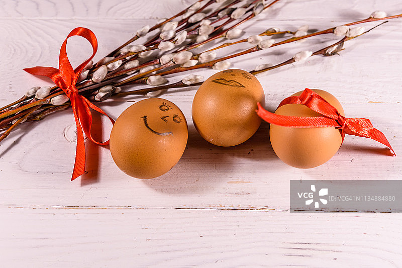 白色木桌上的毛茸茸的柳树花束和复活节彩蛋图片素材