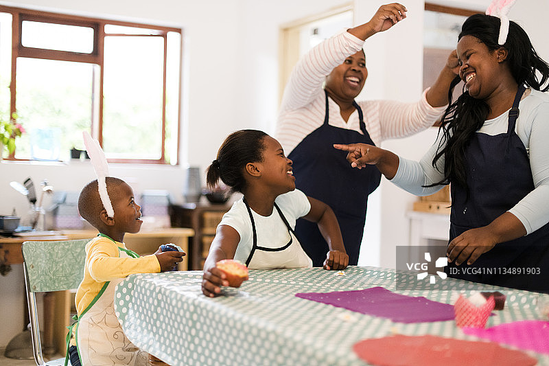 姐妹和孩子们头戴复活节兔子耳朵吃纸杯蛋糕的快乐时光图片素材
