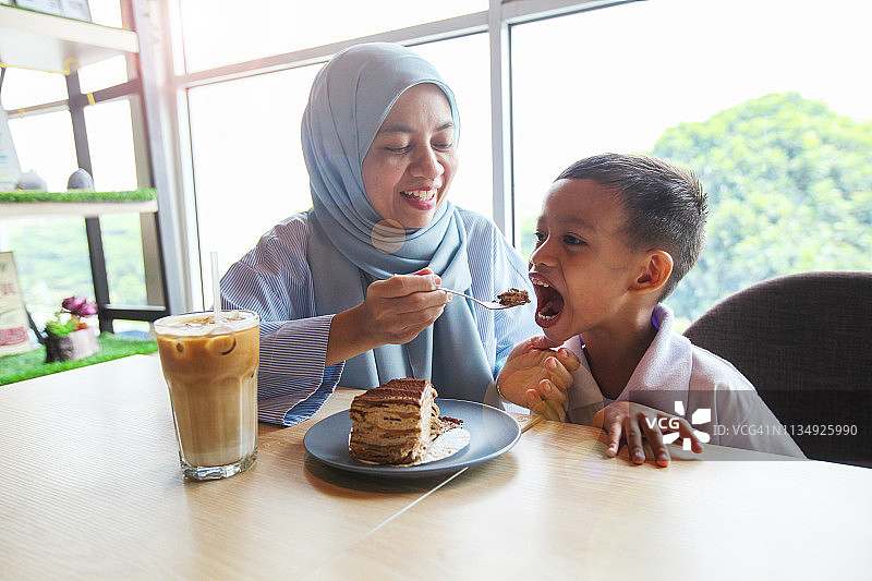戴着头巾的穆斯林母亲与儿子分享蛋糕图片素材