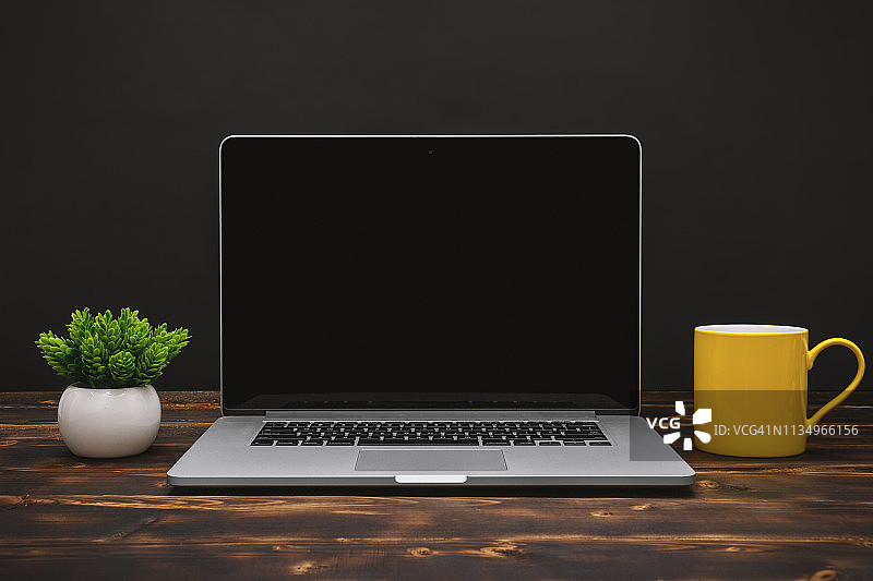 家用办公桌上的笔记本电脑和黄色咖啡杯图片素材