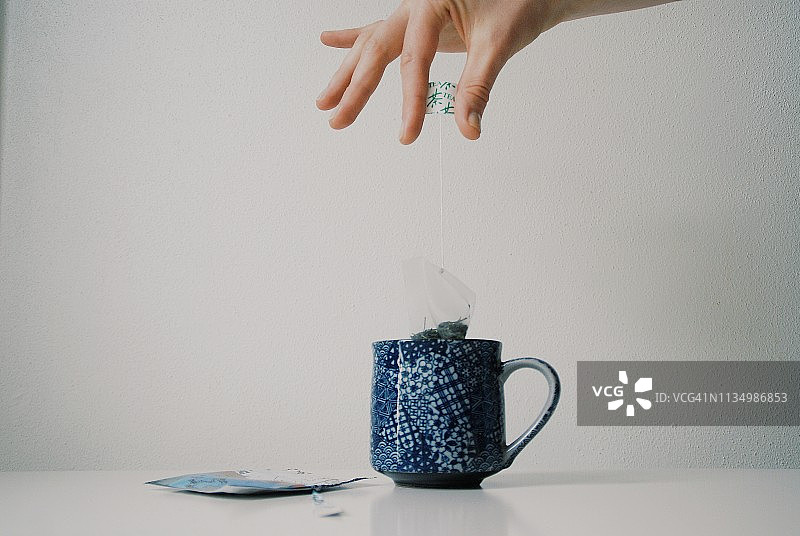 女人手拿茶包放入杯中图片素材