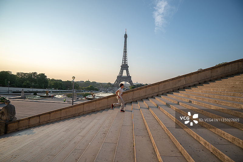 运动型年轻男人在巴黎埃菲尔铁塔上跑步上楼梯图片素材