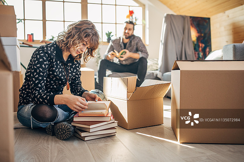 年轻夫妇坐在堆满未拆箱子的新公寓里图片素材