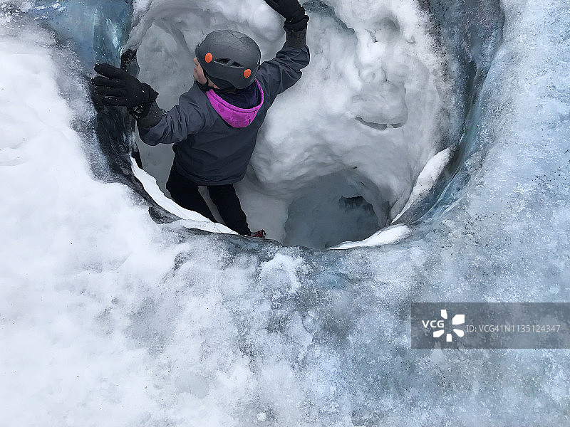 女孩爬出瓦特纳冰川的冰洞图片素材