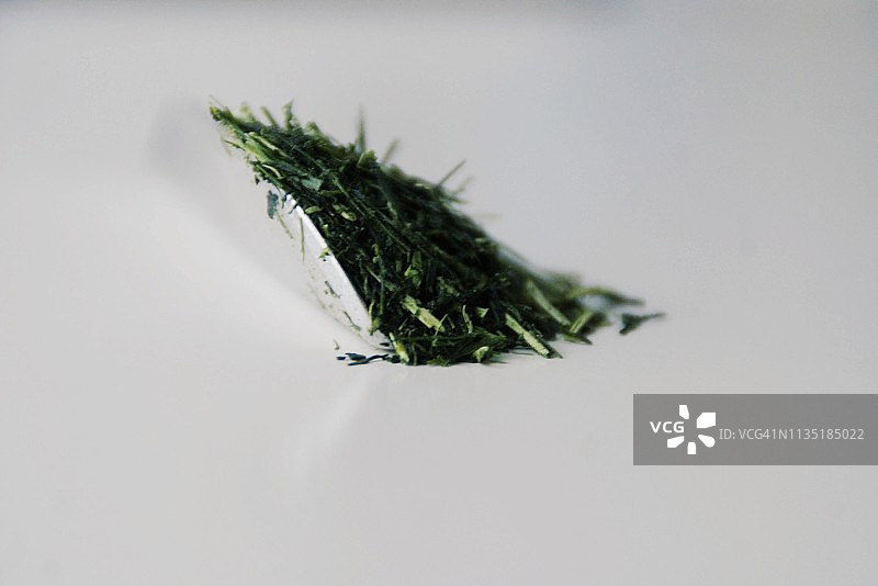 金属茶匙与干燥的茎茶绿茶叶，白色背景，特写图片素材