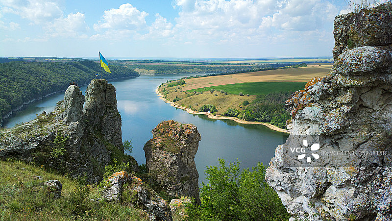 岩石上的乌克兰国旗，可全景欣赏田野和湖泊图片素材