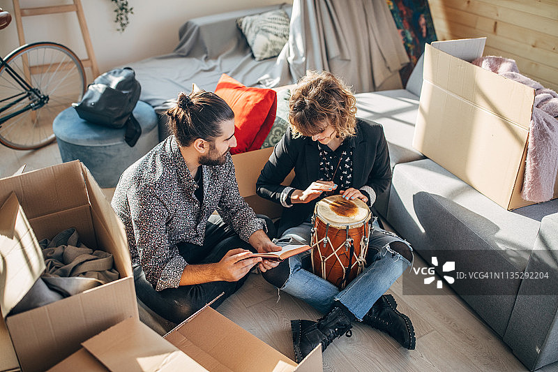 年轻情侣在新家中坐在未拆封的箱子旁图片素材