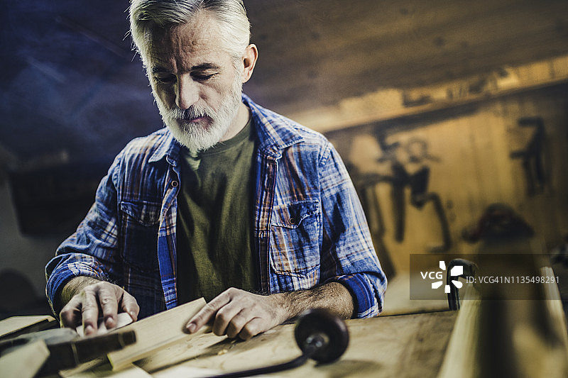 年长的木工在木头上使用砂纸图片素材