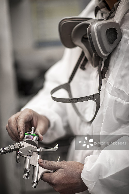 汽车修理店技师在喷漆车间调整喷枪压力图片素材