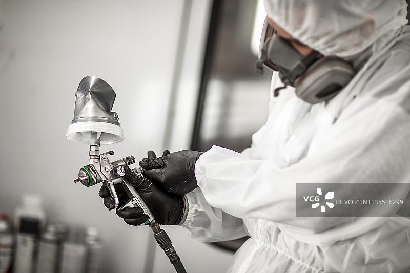 在车身修理厂的喷漆室里，喷漆技师正在调整喷枪的压力图片素材