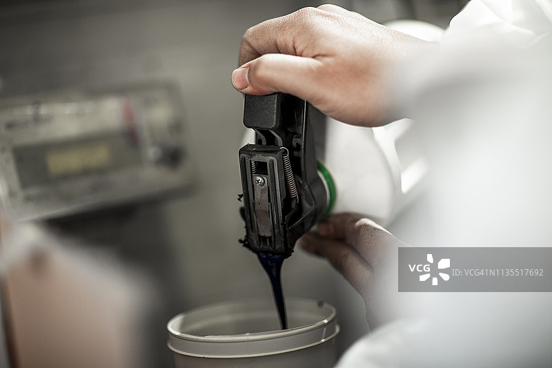 汽车调色师在喷涂容器中倒入并准备油漆图片素材