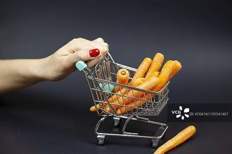 女人推动的购物车里的胡萝卜图片素材