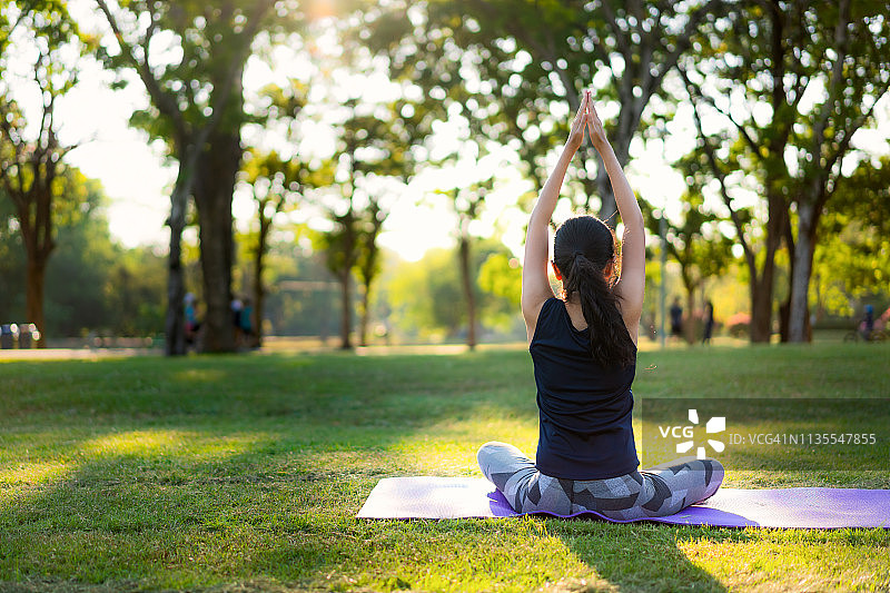 年轻亚洲女子在日落时分的公园练习瑜伽图片素材