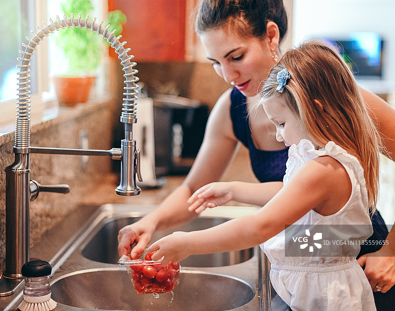 在厨房里工作：母女清洗蔬菜图片素材