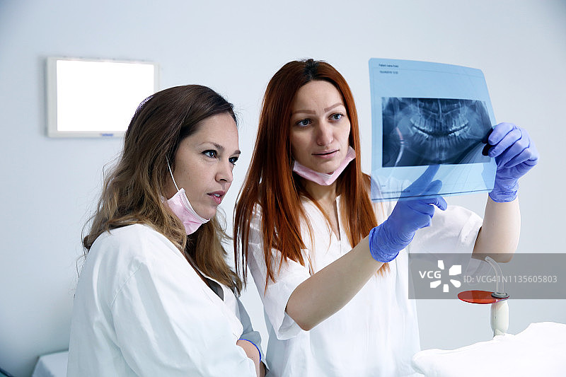 牙医和助手在牙科诊所检查X光片图片素材