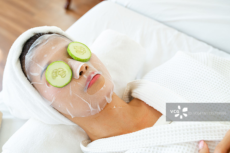 居家水疗：女性面部敷着黄瓜片躺在床上图片素材