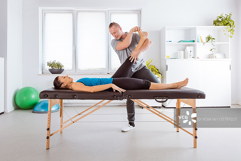 理疗师为年轻女性拉伸腿部图片素材