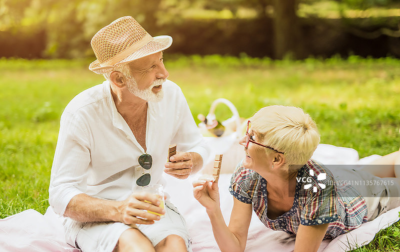 幸福的老年夫妇在户外野餐并吃巧克力图片素材