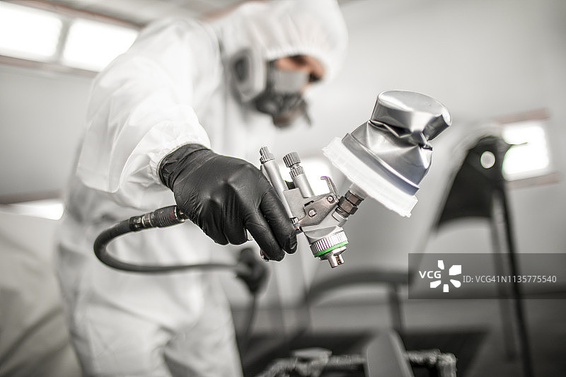 车身修理技师在喷漆房喷涂汽车部件图片素材