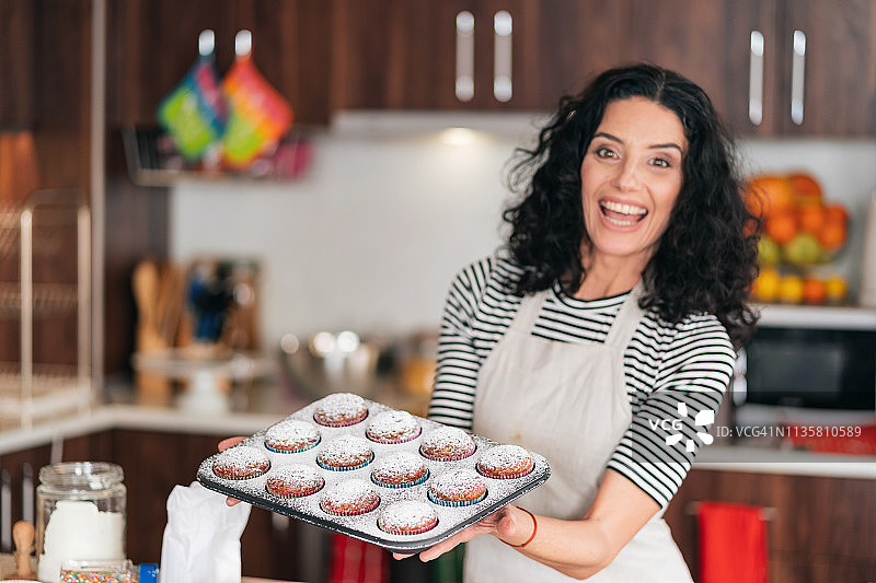 糕点师端着一盘纸杯蛋糕图片素材