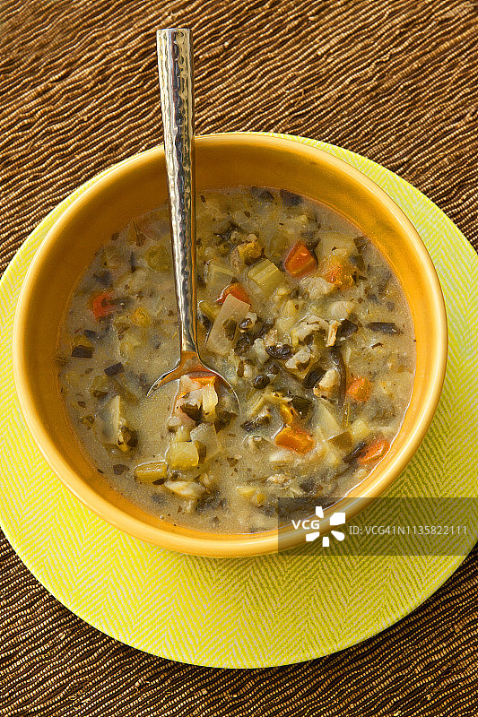 橙色蘑菇蔬菜汤碗与黄色茶碟和勺子图片素材