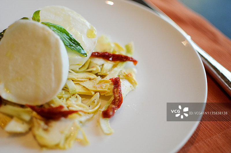 朝鲜蓟和樱桃番茄上的水牛马苏里拉奶酪图片素材