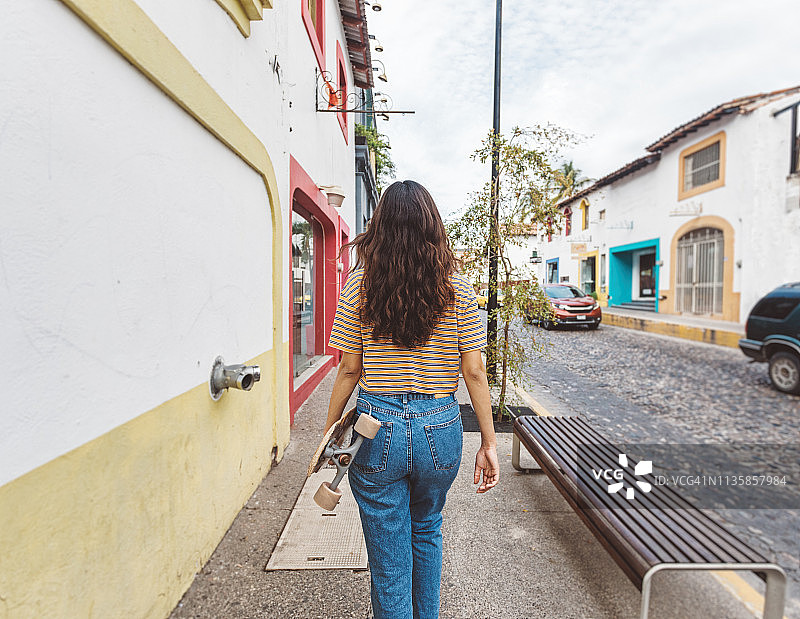 女人长板滑手城市中穿行图片素材