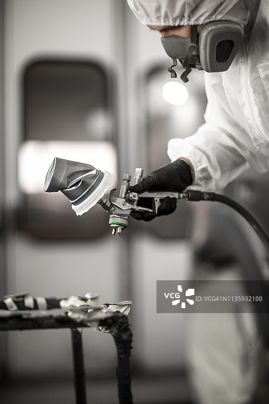 喷漆车间内，喷漆技师为事故中受损的汽车部件喷漆图片素材