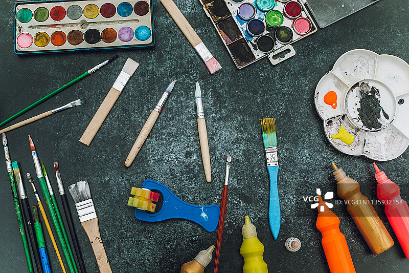 艺术家的工作场所：黑色桌子上的一组彩色颜料图片素材
