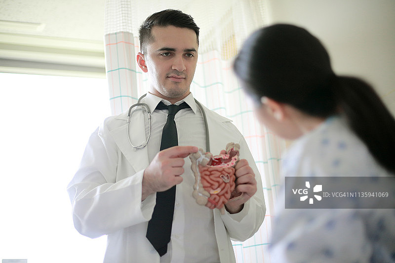 医生在办公室向病人展示肠道模型图片素材