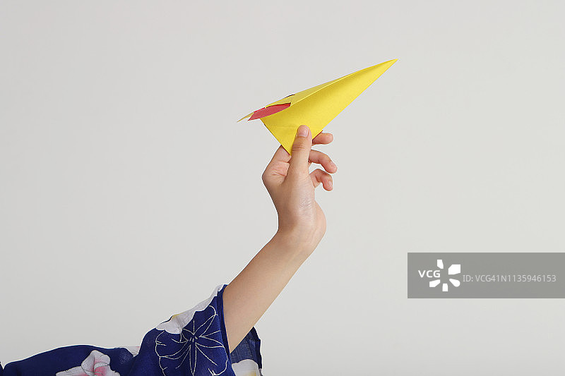 女子拿着黄色纸飞机的手部特写图片素材