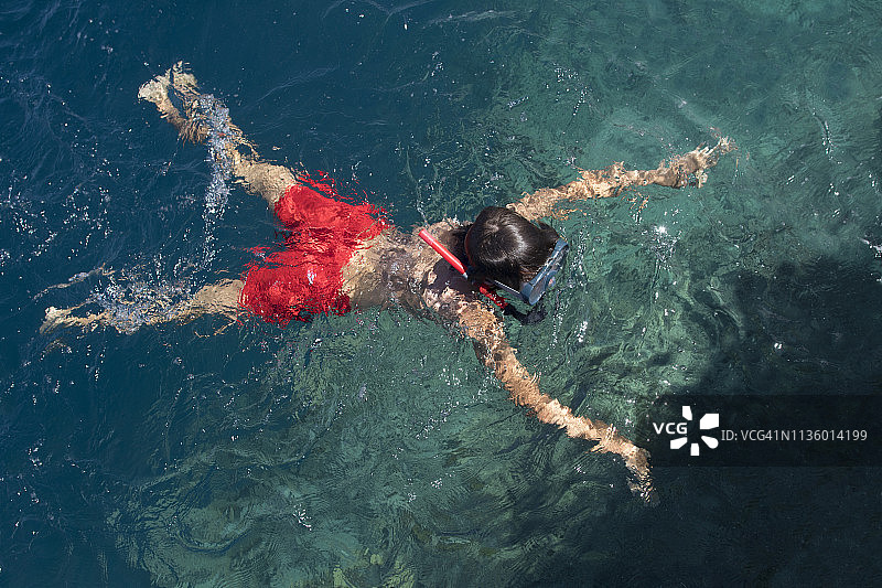 儿童戴着面罩和呼吸管在海里游泳图片素材