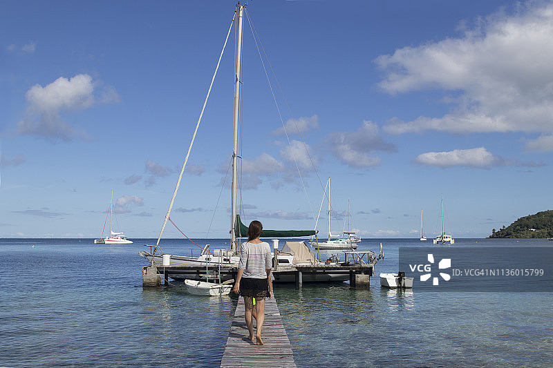 女人在海边木制浮桥上行走图片素材
