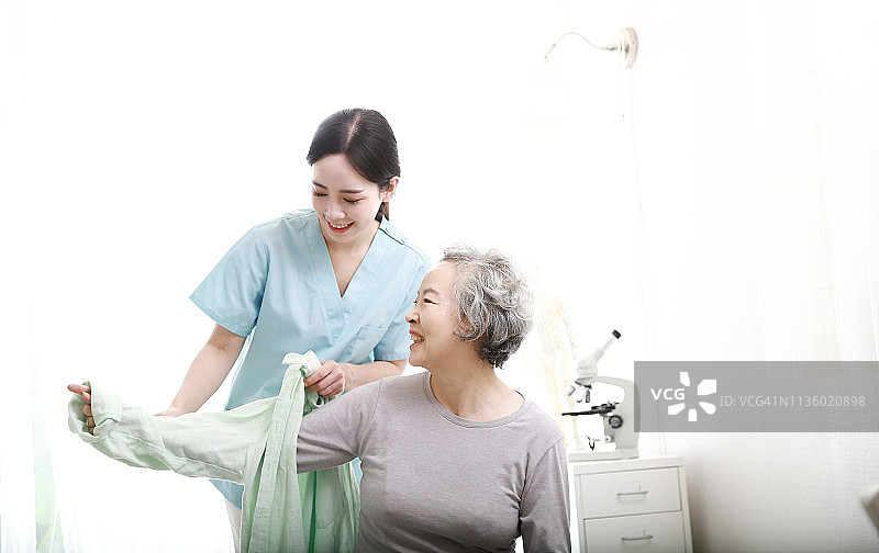 护士帮助年长女性穿衣服图片素材