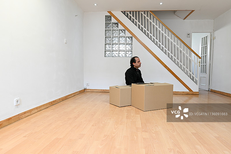 男人在空房间里看着搬家纸箱图片素材