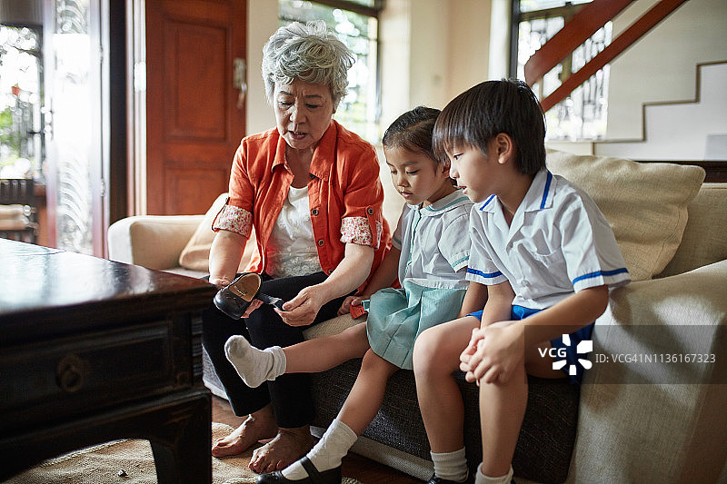 祖母帮助女孩穿上学鞋图片素材