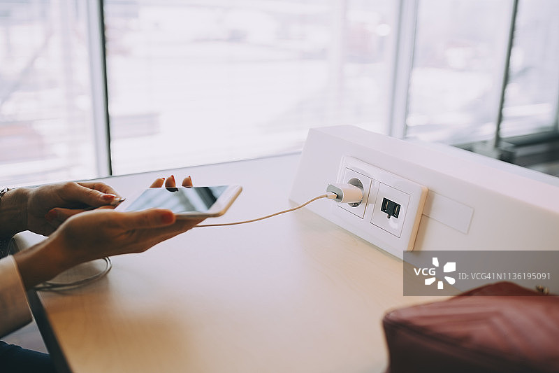 年轻女商人在机场候机区充电的局部照片图片素材