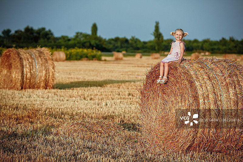 坐在草垛上的小女孩图片素材