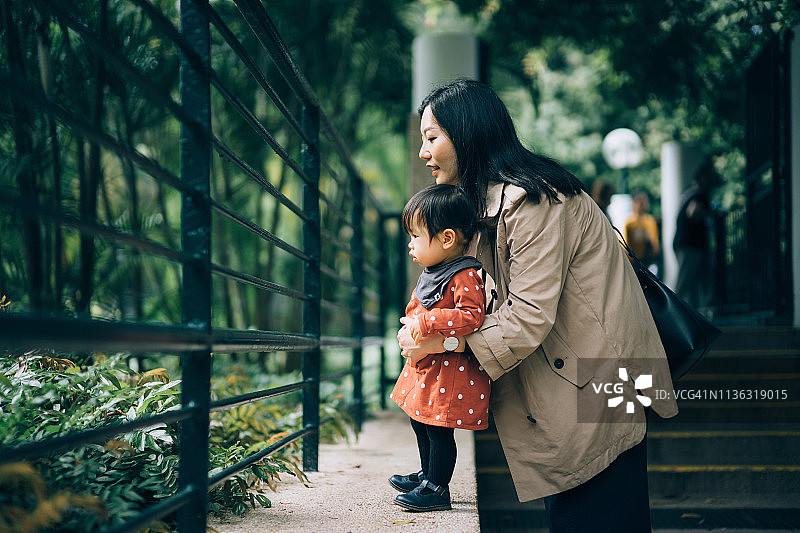 母亲和女儿在公园里隔着栅栏看可爱的小动物图片素材