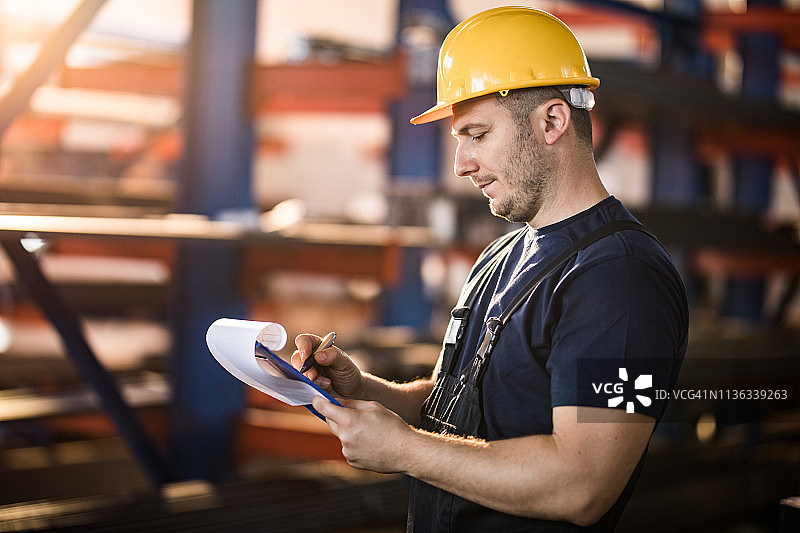 在仓库里写东西的中年体力劳动者图片素材