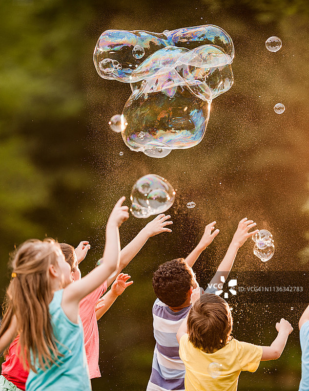 一群孩子在公园里玩彩虹泡泡，玩得很开心图片素材
