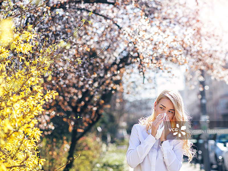 在鲜花盛开的花园里打喷嚏的女人图片素材