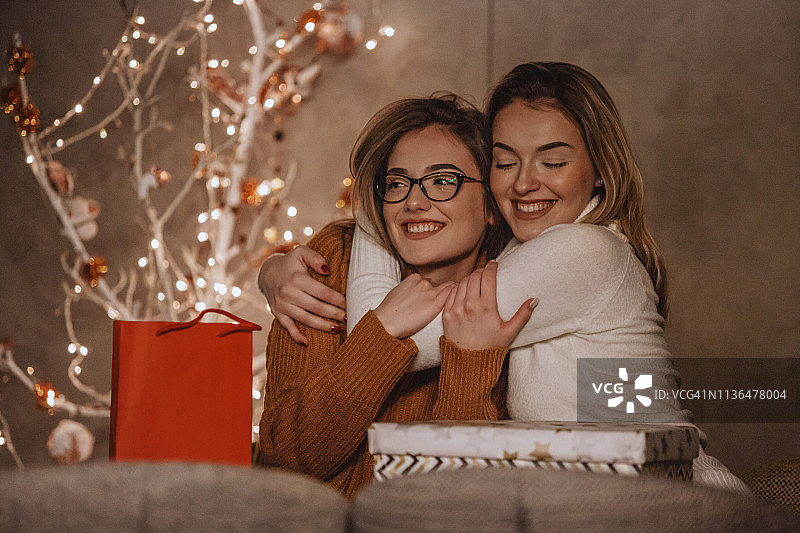 姐妹们在圣诞树旁拥抱图片素材