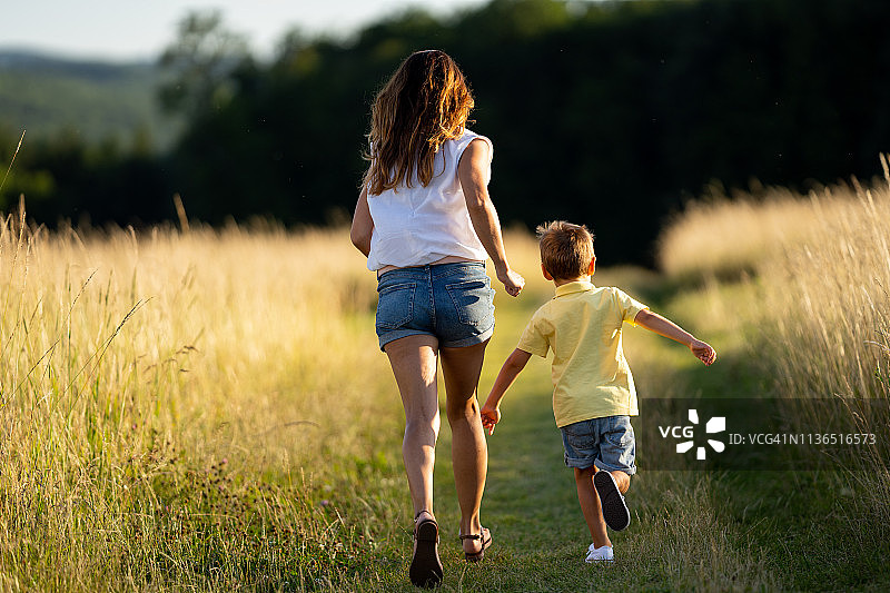 母子在夏日草地上奔跑的背影图片素材
